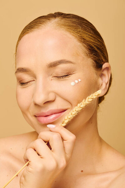 Эта молодая женщина с сияющей кожей мягко держит пшеницу, обнимая мирный момент.