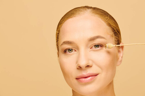 Молодая красивая женщина плюс размер мягко наносит кожу на лицо, демонстрируя уход за собой.