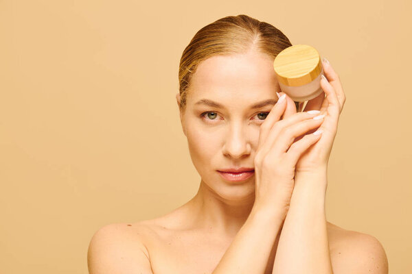 Молодая красивая женщина плюс размер представляет банку с кожей, принимая ее природную красоту.