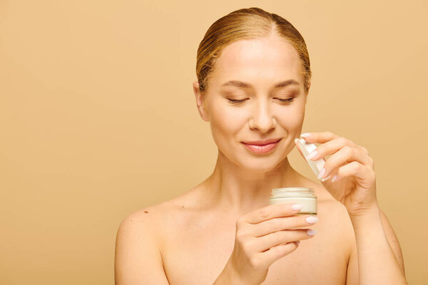 A young, confident woman delights in applying cream to enhance her natural beauty during self care.