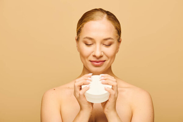The young woman closes her eyes, savoring the soothing aroma of her skincare product.