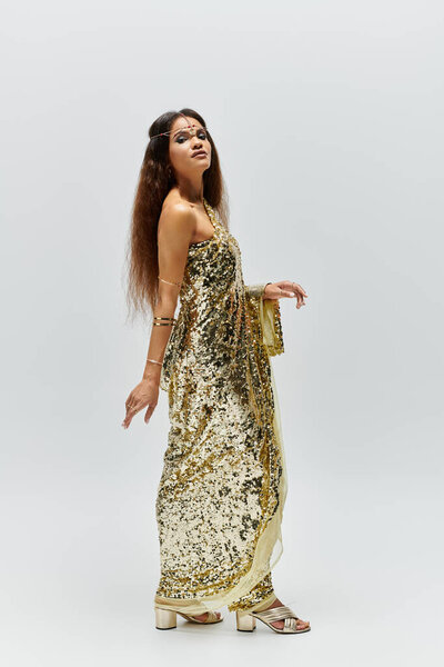 An enchanting African American woman captivates in a golden dress, showcasing elegance in a studio.