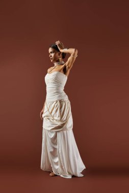 A stunning African American woman exudes confidence in a white dress, showcasing elegance in a studio setup. clipart