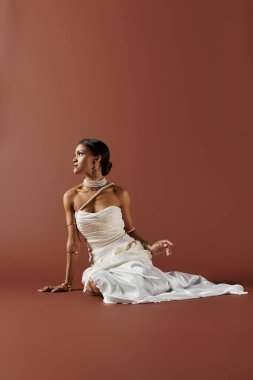 A stunning African American woman, dressed in a white gown and pearls, exudes elegance against a warm brown backdrop. clipart