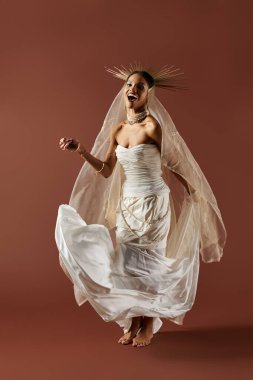 Beyaz bir elbiseyle süslenmiş ve incilerle süslenmiş güzel kadın, dingin bir stüdyoda ilahi bir aura yayar..