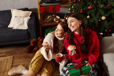 İki kız arkadaş rahat kazaklar içinde Noel 'i oturma odalarında hediyeler ve hediyelerle kutluyor..