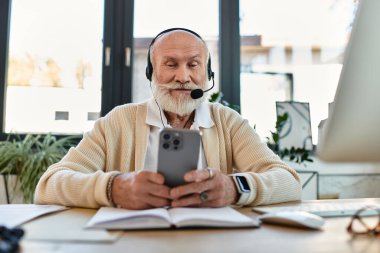 A seasoned manager engages in a conversation using his smartphone in a bright workspace. clipart