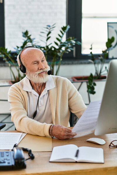 A stylish senior businessman with a beard focuses on important documents in his contemporary office.