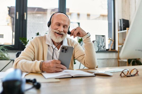 A senior businessman with a beard is engaged in a video call, smiling at his smartphone while working.