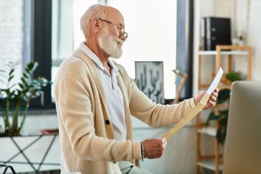Sakallı deneyimli bir işadamı şık bir ofiste otururken önemli belgeleri analiz eder..