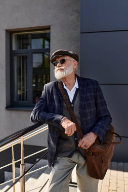Sakallı, modaya uygun bir son sınıf öğrencisi, güz için sıcak giyimli, gösterişli, modern bir binayla rahatlıyor..
