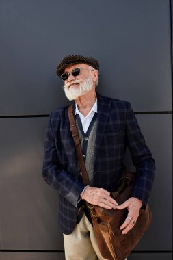 Sakallı şık bir son sınıf öğrencisi, gösterişli bir binanın yanında dikilirken sonbahar gününün tadını çıkarıyor..