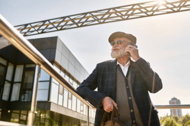 Telefonunda sakallı, kareli ceket giymiş ve sonbaharda düz şapka takmış şık bir son sınıf öğrencisi..