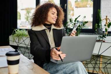 A woman engages with her phone while focused on her laptop surrounded by plants. clipart