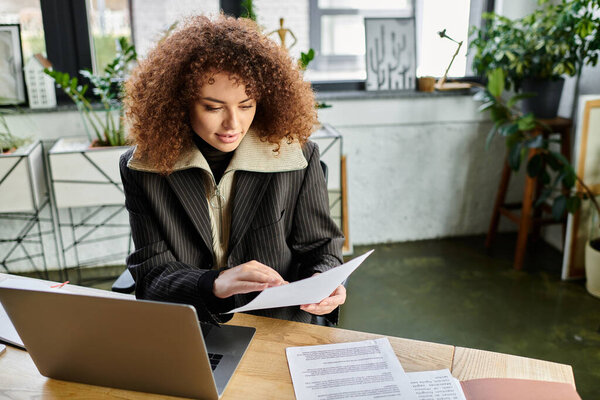 A woman examines papers intently at a modern desk filled with greenery and morning sunshine.