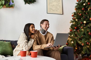 Bir çift Noel süslemeleri ve bir ağaçla çevrili evde eğleniyor..