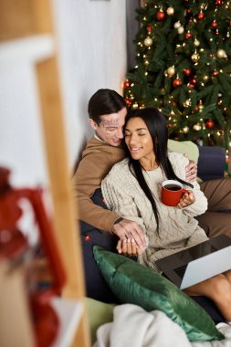 Güzel dekore edilmiş Noel ağacının yanında samimi bir çift sıcaklığı ve sevinci paylaşır..