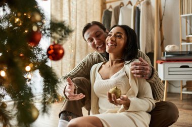 Sevgi dolu bir çift Noel ağacının sıcaklığını paylaşıyor ve gülüyor..