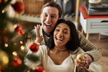Bir çift, Noel 'i evde, şenlikli süslemelerle kutluyor..