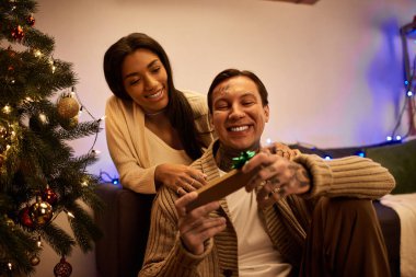 Bir çift, evdeki rahat bir Noel ortamında hediyelerini değiş tokuş ederek özel bir anın tadını çıkarıyor..