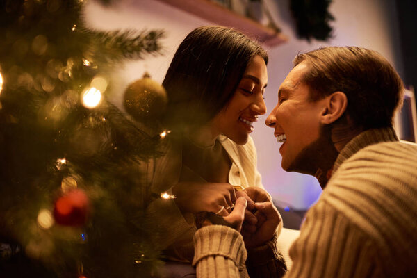 Пара наслаждается нежными моментами вместе, в окружении теплых праздничных украшений.