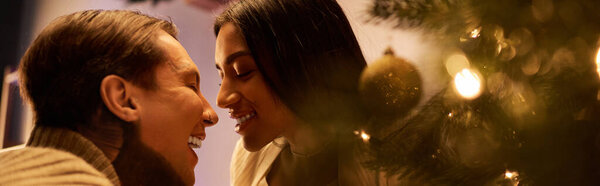 Пара обнимается в окружении мерцающих огней и праздничных украшений в своем доме.