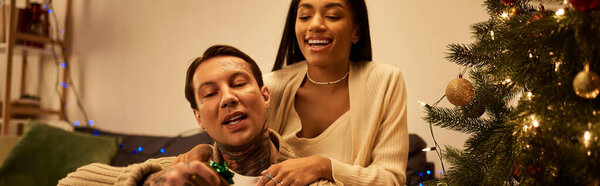 Любящая пара делится смехом и теплом, украшая свой дом на Рождество.