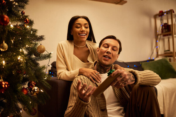 Два человека обнимают дух Рождества, обмениваясь теплом и смехом в своем уютном доме.