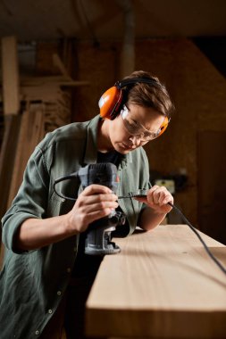 A skilled carpenter works diligently on wood with power tools, enveloped in workshop creativity and concentration. clipart