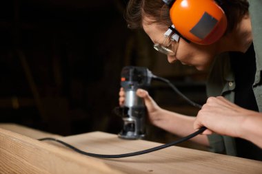 A dedicated carpenter shapes wood meticulously in her workshop, showcasing craftsmanship and focus. clipart