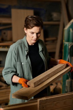 Focused on her work, a skilled carpenter shapes wood with precision in a bustling workshop environment. clipart