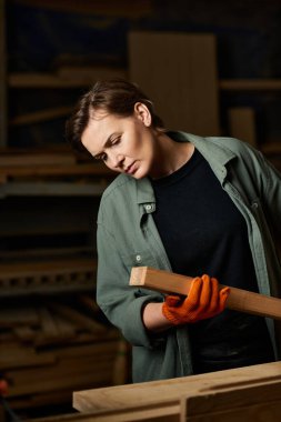 A skilled carpenter focuses intently on shaping wood, showcasing craftsmanship in her workshop. clipart