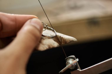 Bir zanaatkar, sakin bir ortamda hassas aletler kullanarak gümüş bir yüzük üzerinde titizlikle çalışır..