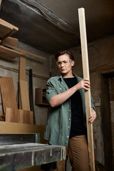 A dedicated female carpenter meticulously working with a wooden plank in her workshop, surrounded by tools.