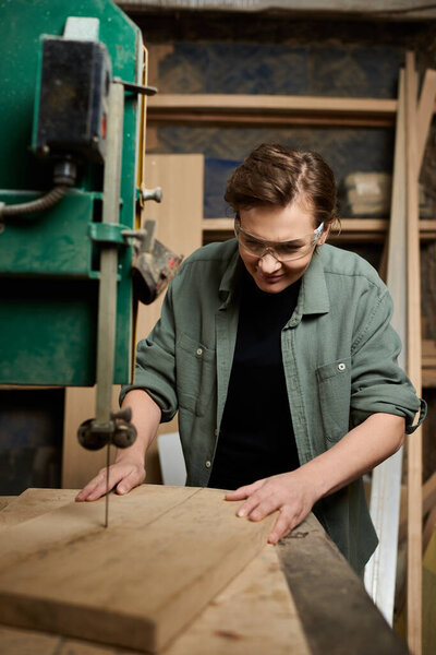 A dedicated female carpenter focuses on crafting wooden pieces in her well-equipped workshop.