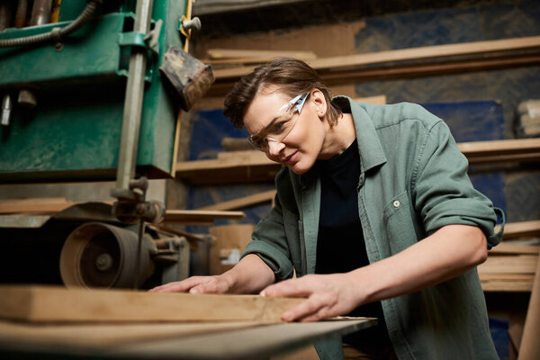 A skilled female carpenter focuses intently as she meticulously shapes wood in her busy workshop.