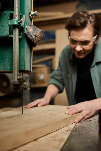 A dedicated female carpenter delicately works on wood in her well-equipped workshop, focused and skilled.