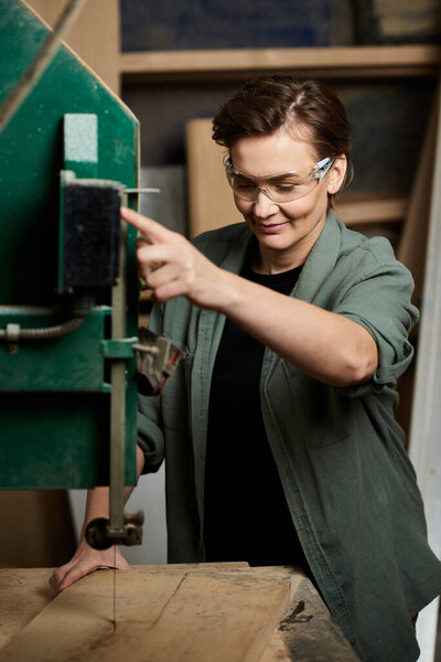 A skilled carpenter focuses intently while working with machinery in her well-equipped woodshop.