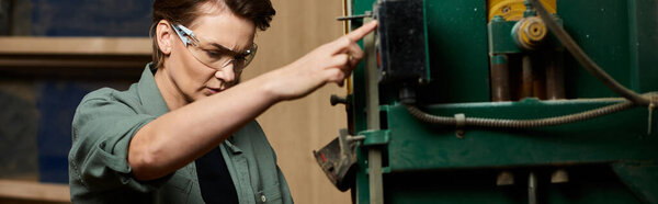 In a lively workshop, a skilled female carpenter focuses intently on operating woodworking machinery.