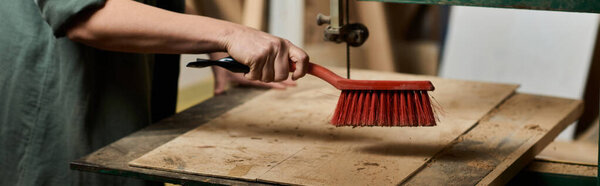 carpenter meticulously cleans wood surfaces in her vibrant workshop filled with tools and materials.