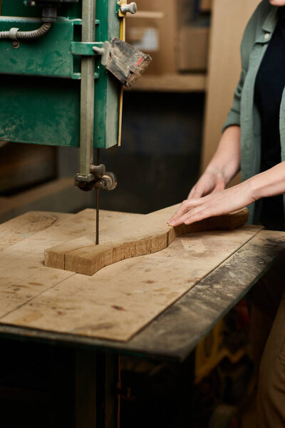 A focused carpentry expert carefully shapes a wooden piece at her workshop, showcasing craftsmanship and skill.
