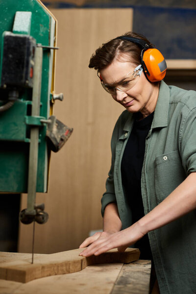 A dedicated carpenter focuses on crafting wood with precision in her well-equipped workshop.