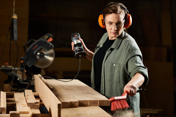 In her workshop, a talented female carpenter focuses on shaping wood while expertly managing her tools.