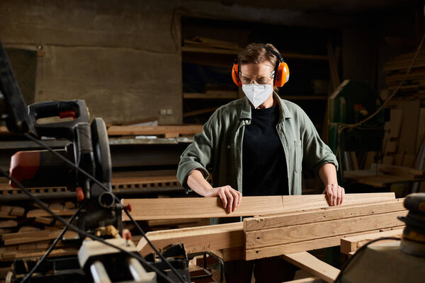 A focused carpenter works diligently with wooden planks in a well-equipped workshop, demonstrating craftsmanship.
