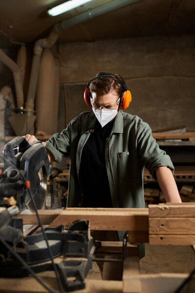 A dedicated female carpenter is using a saw to shape wood, surrounded by tools in a lively workshop.