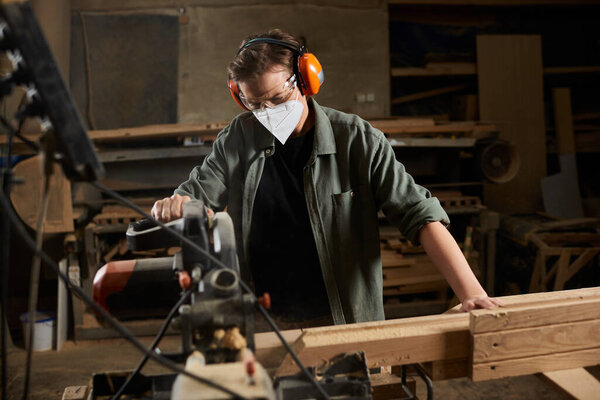 A skilled carpenter works diligently with wood, demonstrating craftsmanship and attention in her workshop.