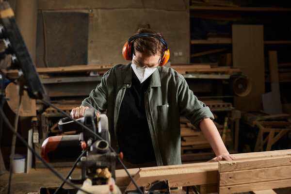 A skilled carpenter works diligently with wood, showcasing craftsmanship in a well-equipped workshop.