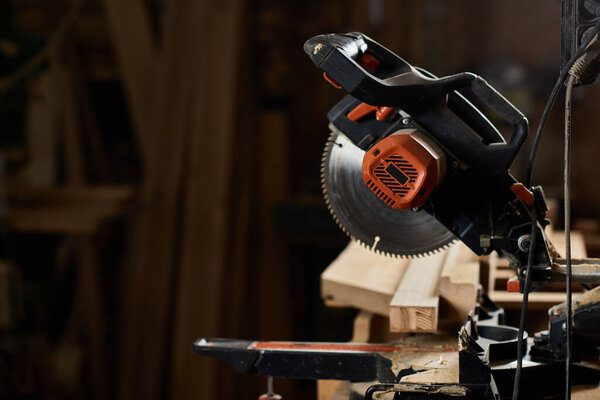 a miter saw in a rustic workshop filled with wood and dust