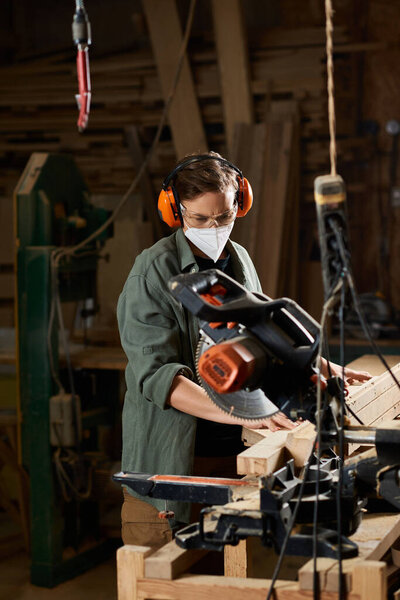 Целенаправленная плотница использует электроинструменты для создания сложных деревянных конструкций в своей мастерской..