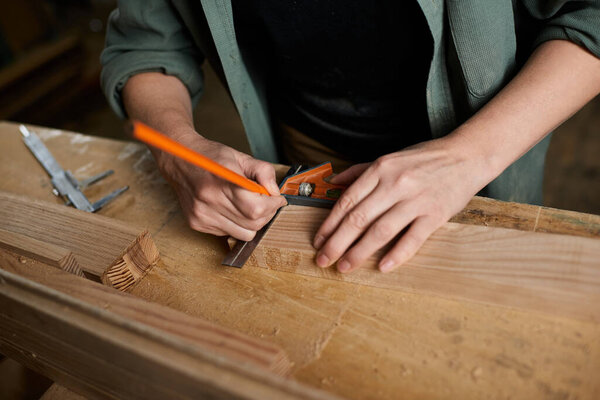 A skilled female carpenter focuses on precision, measuring and marking wood carefully in her workspace.